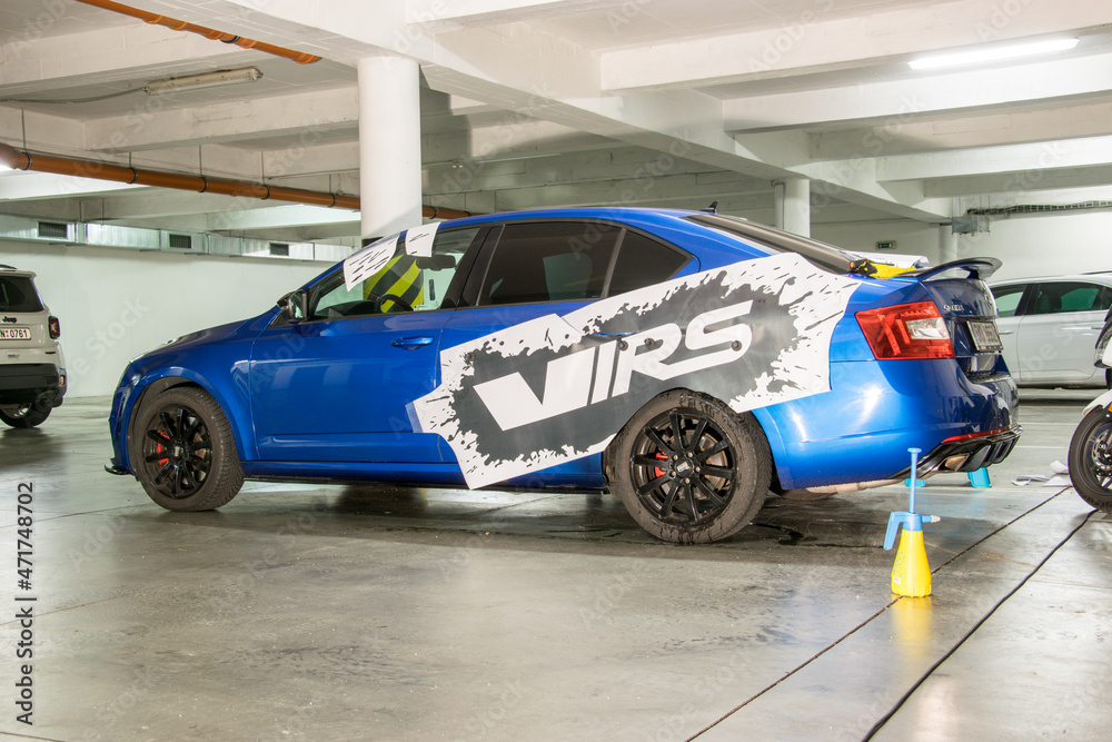 Installation of black vinyl gloss stickers on the side of a blue sports car  parked in a garage. Stock-foto | Adobe Stock