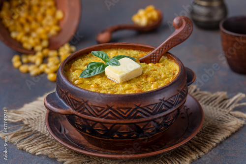 Delicious cornmeal baked porridge in a pot. Vegan hominy porridge with sweet corn and carrot. Dark background, selective focus, close up. photo