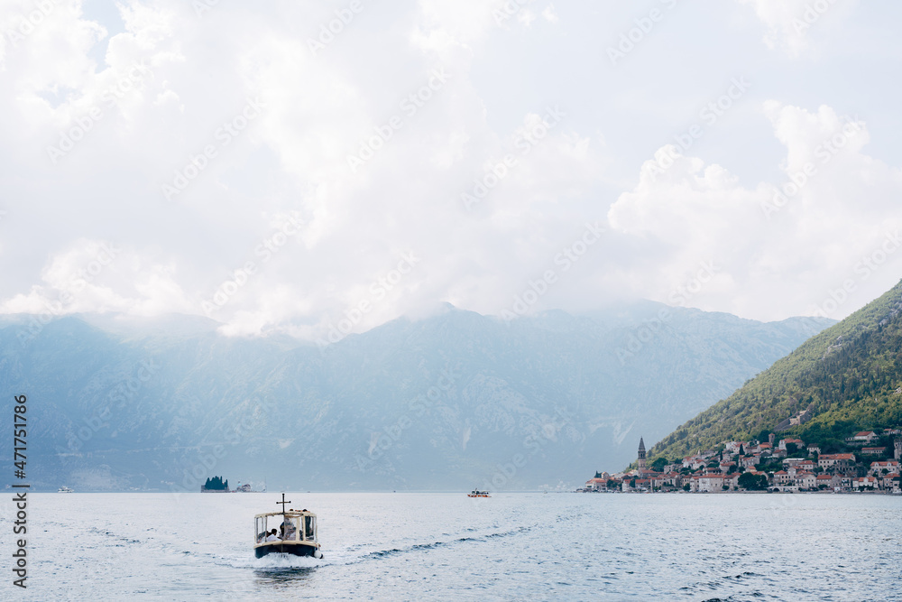 Motor boat sails along the Kotor Bay against the backdrop of the town of Perast. Montenegro