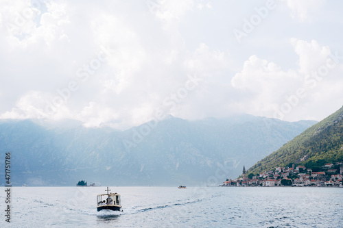 Motor boat sails along the Kotor Bay against the backdrop of the town of Perast. Montenegro © Nadtochiy