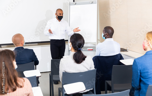 latino male businessman gives advice to manager in meet room during pandemic