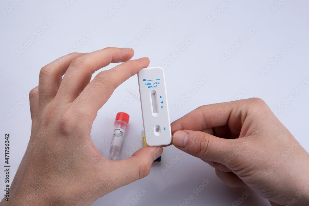 isolated shot of two hands holding a negative result rapid express antigen coronavirus covid-19 pandemic test sample, a lancet and solution on white background isolated shot of two hands holding a negative result rapid express antigen coronavirus covid-19 pandemic test sample, a lancet and solution on white background
