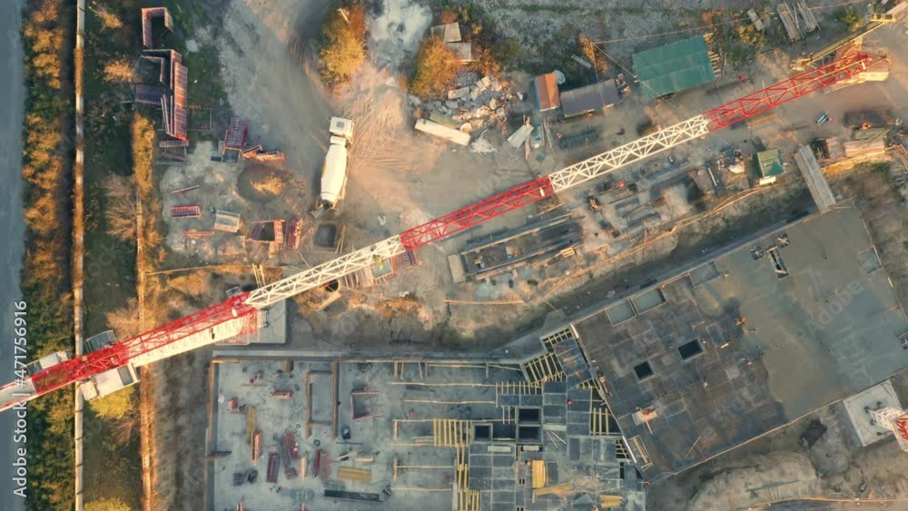 Aerial top down view of a construction site of with a dwelling house in a course of building with tower crane, concrete mixer