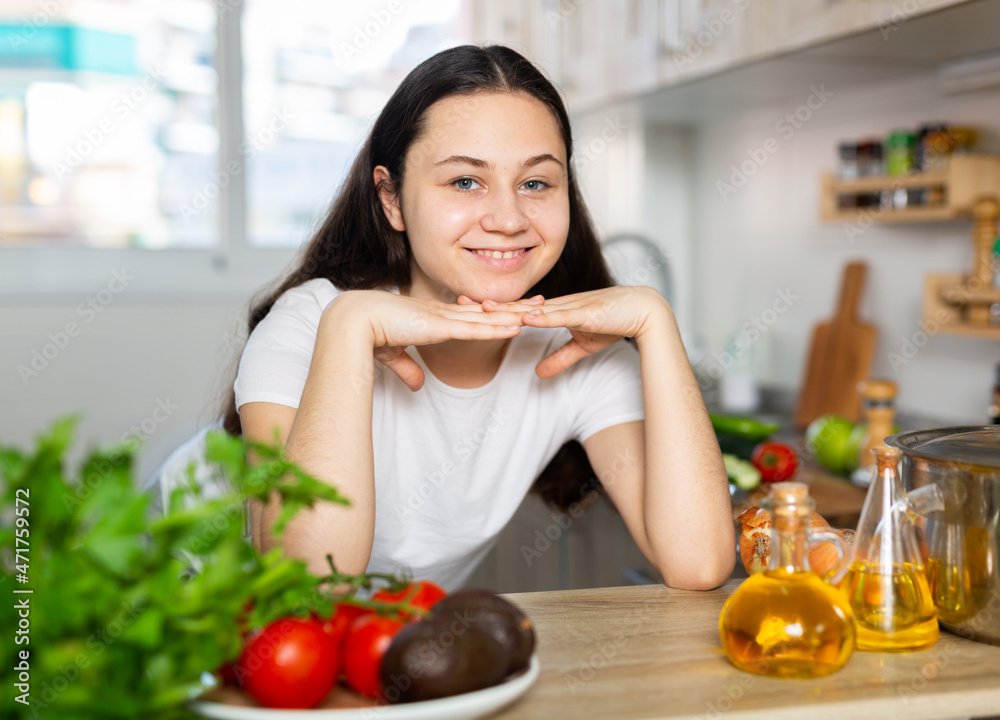 Young beautiful modern woman stands near table on kitchen at home