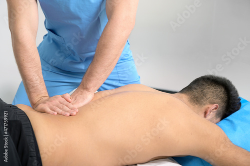 Physiotherapist massaging the back of a young athlete in the sports rehabilitation clinic. High quality photo .