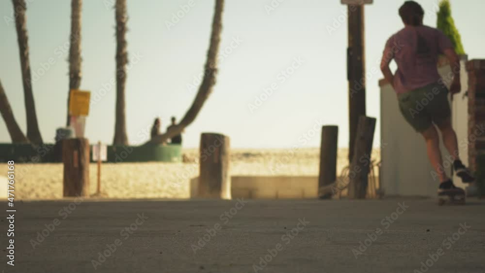 Skater boy do trick rides away in coastal pathway of Los Angeles, static view Skater boy do trick rides away in coastal pathway of Los Angeles, static view