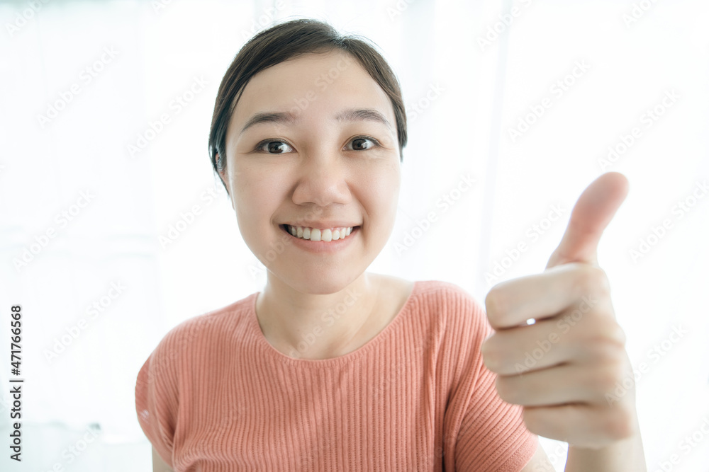 Happy Asian young woman showing her thumbs up and smiling to camera close up. Happy Asian young woman showing her thumbs up and smiling to camera close up.