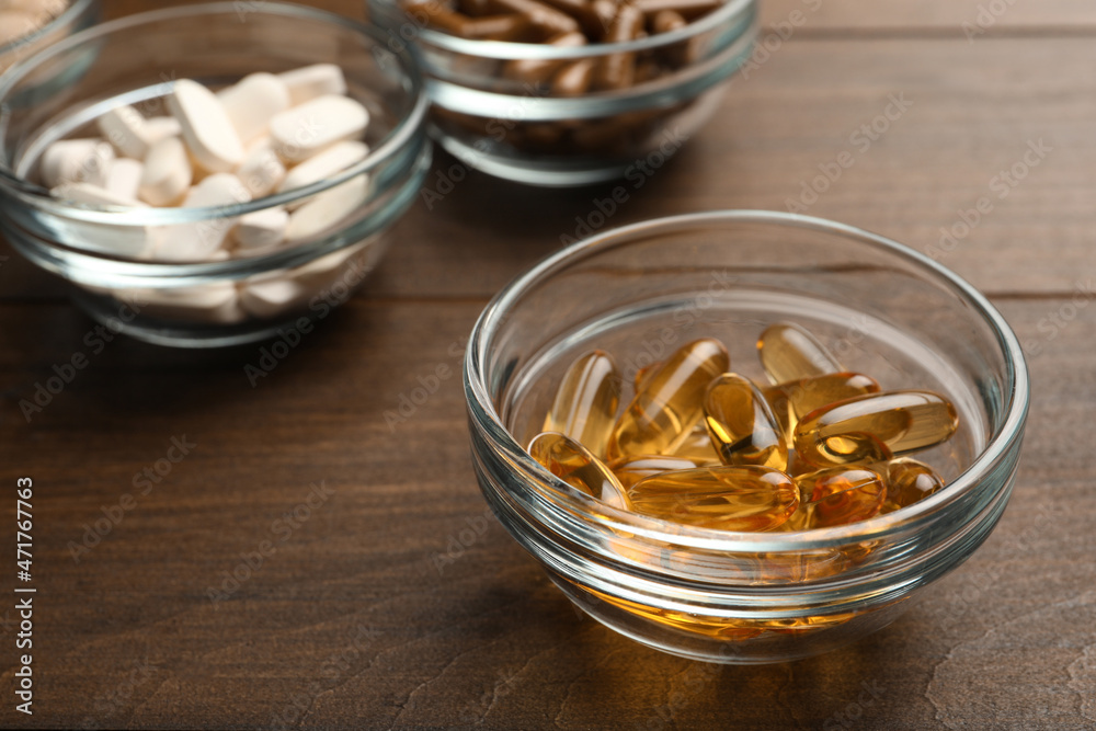 Different dietary supplements in glass bowls on wooden table, closeup Different dietary supplements in glass bowls on wooden table, closeup