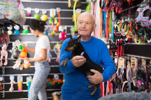 Mature man chooses collar for his dog at a pet shop