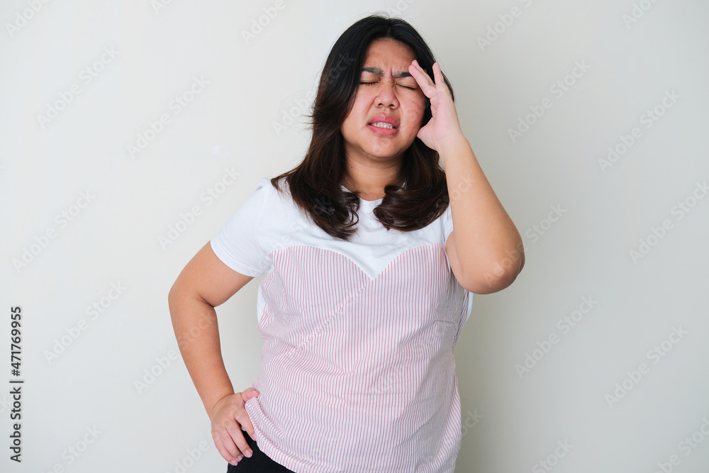 Adult Asian woman touching side of her forehead showing stressed gesture