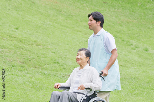 介護士と車椅子に乗る高齢者 屋外
