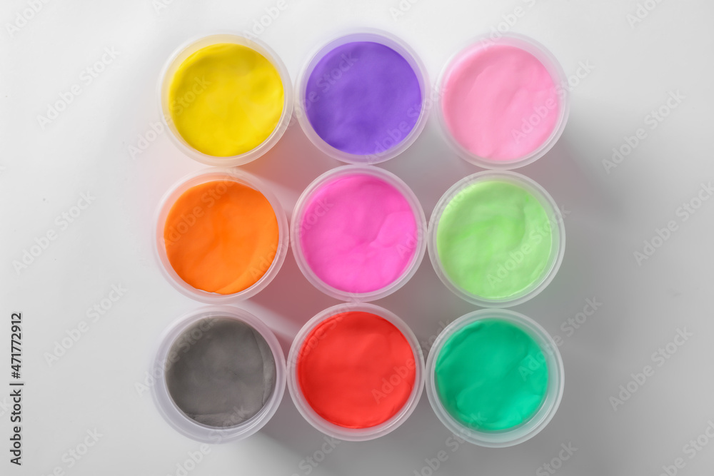 Plastic containers with different color play dough on white background, top view Plastic containers with different color play dough on white background, top view