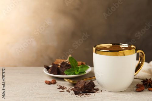 Yummy hot chocolate in cup on white wooden table, space for text