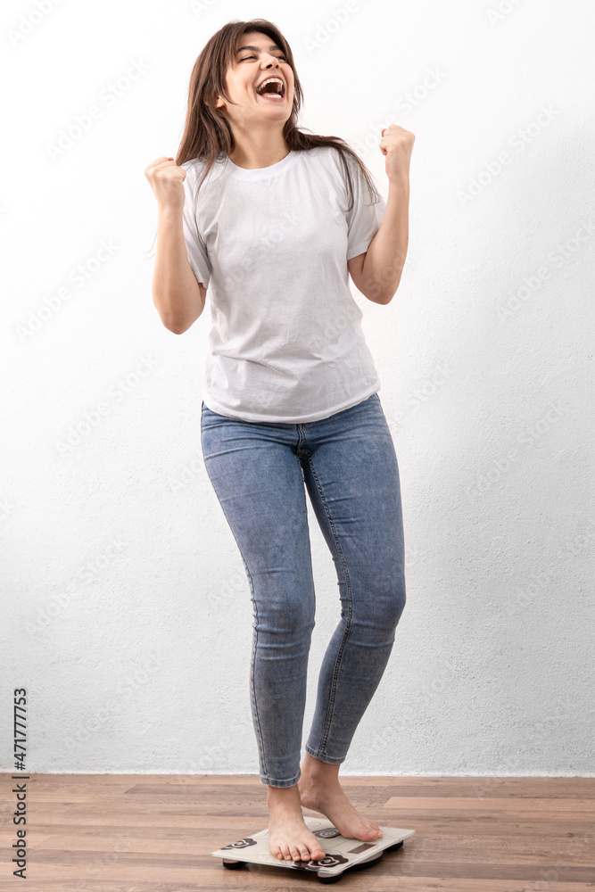 Φωτογραφία Happy girl is weighed on the scales at home, the joy of losing weight