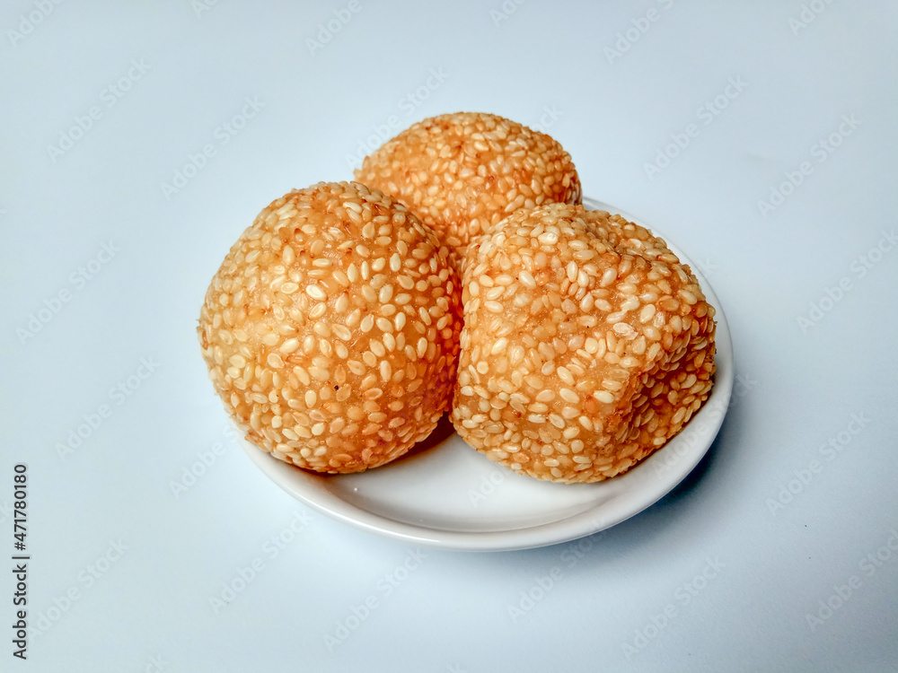 Three fried sesame balls with mung beans filling, called onde-onde in Indonesia, placed in a white small plate. Three fried sesame balls with mung beans filling, called onde-onde in Indonesia, placed in a white small plate.