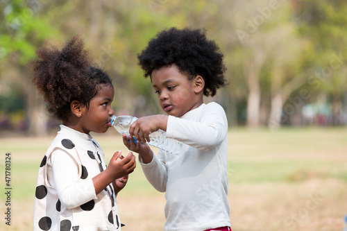 African American children drinking water while playing  in the park photo