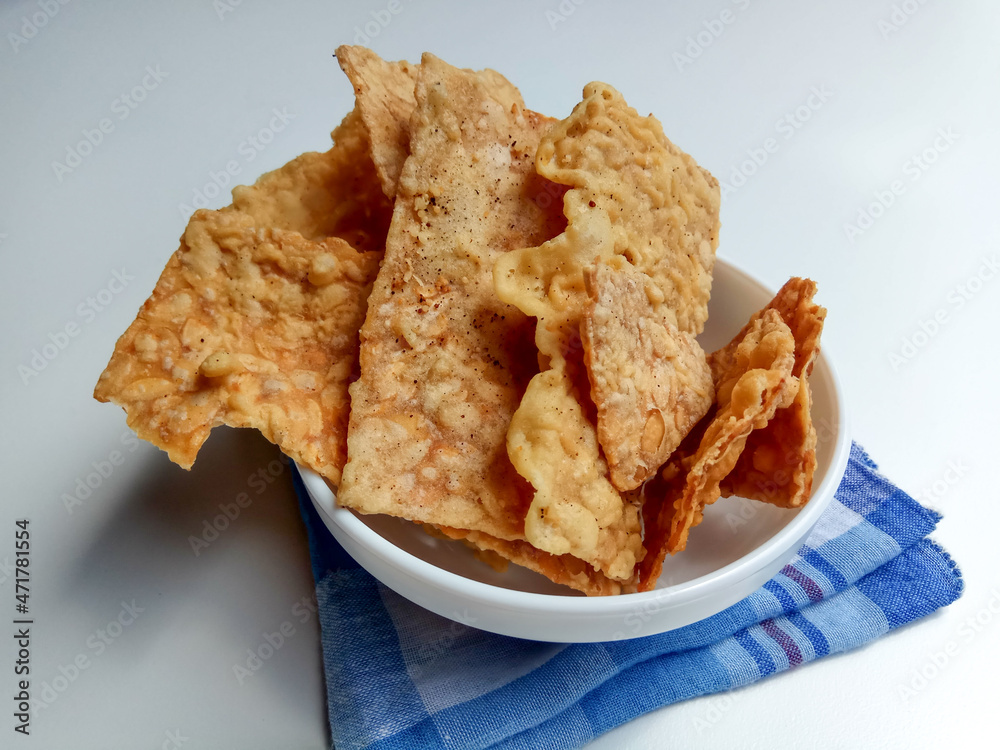 Keripik tempe or tempeh crackers. Inside a white bowl, isolated in white background Stock Photo