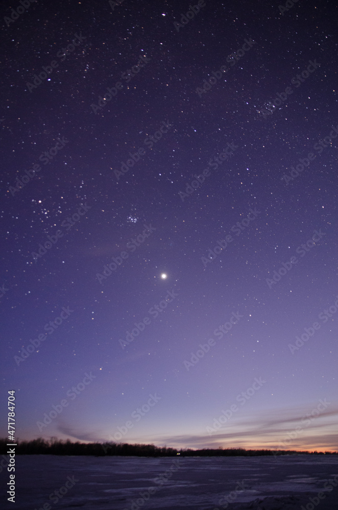 View of the starry sky over the Irtysh river covered with ice
