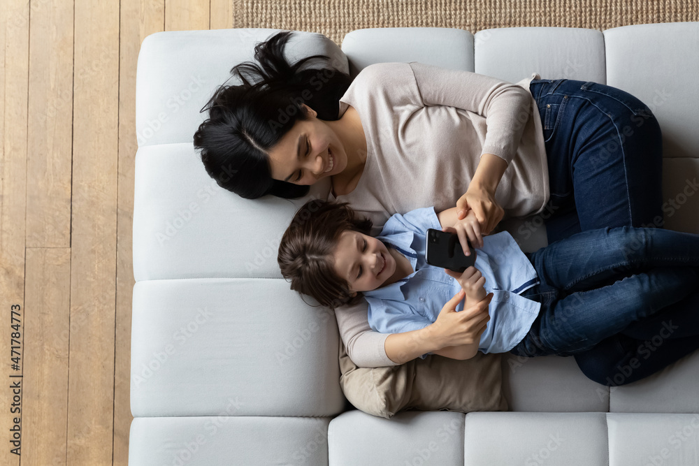 © fizkes - Woman and little 6s son lying on cozy sofa with smartphone, above view. Family spend leisure at home using modern tech usage, play games, buy goods, enjoy new cool amusing mobile app for kids concept © fizkes - Woman and little 6s son lying on cozy sofa with smartphone, above view. Family spend leisure at home using modern tech usage, play games, buy goods, enjoy new cool amusing mobile app for kids concept
