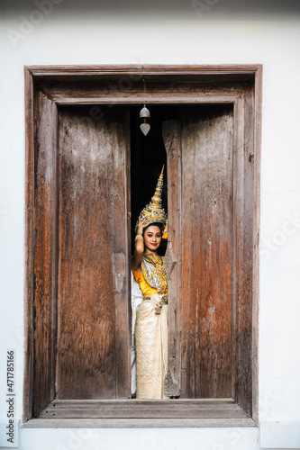 A young woman is wearing a chada that is a Khon costume. by the window photo