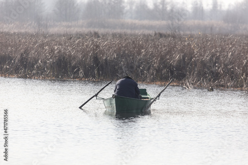 A man in a boat is fishing in a pond