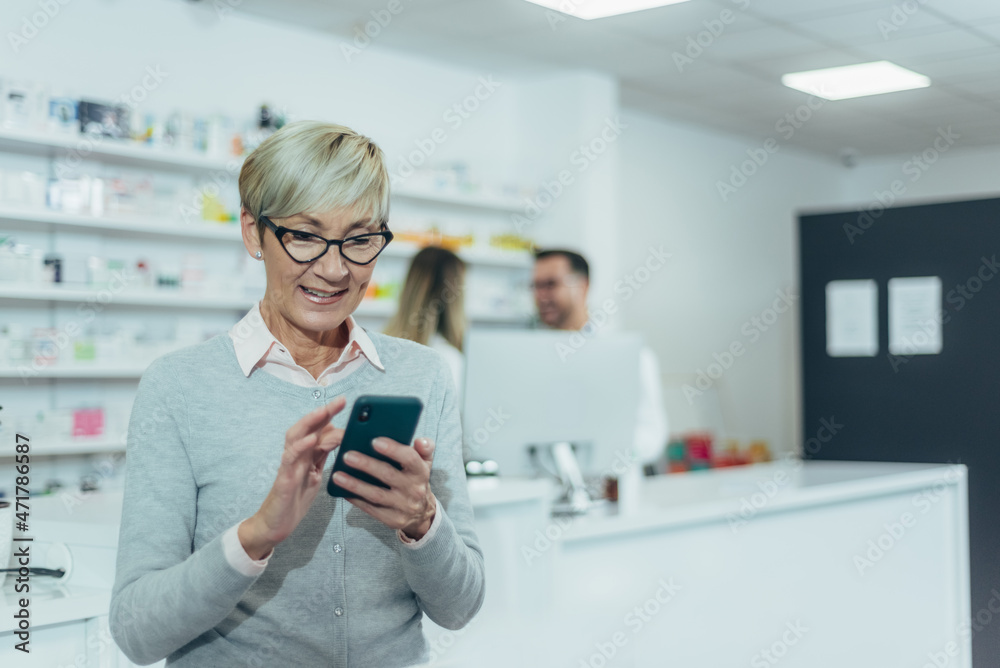 Smiling senior female patient in a pharmacy using smartphone Smiling senior female patient in a pharmacy using smartphone