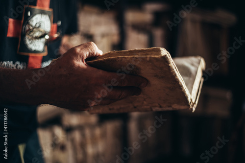 Senior man hands holding an old book in a library