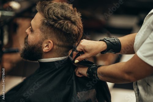 Man is being prepared for a haircut while sitting in chair at barbershop