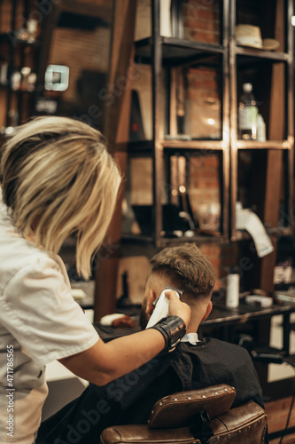 Young bearded man getting haircut by hairdresser