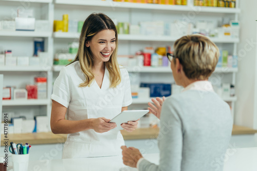 Female pharmacist selling medications at drugstore to a senior woman customer photo