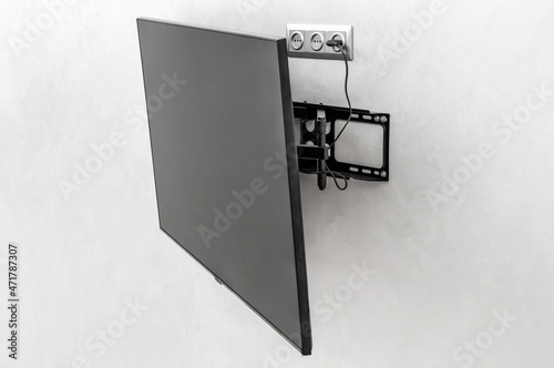 Modern tv hanging on the wall. Tv mounted with special fasteners in the room. photo