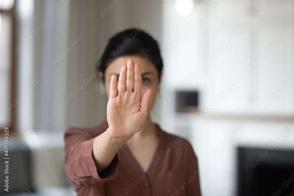 Close up serious young indian woman showing stop sign, protesting against domestic violence, saying no to abuse bullying, denying gender or racial discrimination, nonverbal language concept. Close up serious young indian woman showing stop sign, protesting against domestic violence, saying no to abuse bullying, denying gender or racial discrimination, nonverbal language concept.