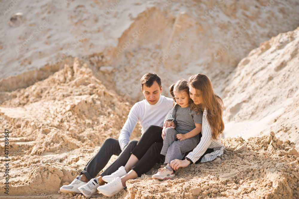 A family of three is sitting among mountains of sand 3350.