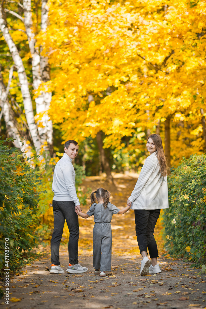 Fototapeta premium Dad, mom and daughter are walking in the autumn forest 3391.