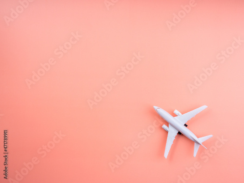 Plane model on pastel pink color background with copy space, top view, minimal style. White airplane, flat lay design. Flight, travel concept.