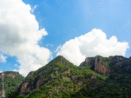 Nature background. Green tree, jungle on the beautiful shape mountain on blue sky and fluffy cloud with sunshine on sunny day.