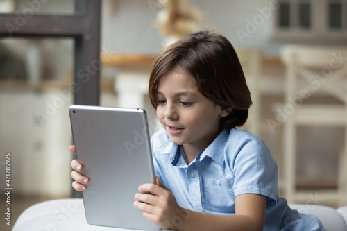 Close up lovely little boy relaxing at home alone with wireless digital tablet device. Parental control software apps, children safe usage of modern tech, cyberspace, internet, fun and leisure concept © fizkes