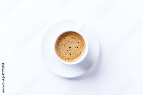 Cup of coffee on bright paper background. Top view. Close up. Copy space.