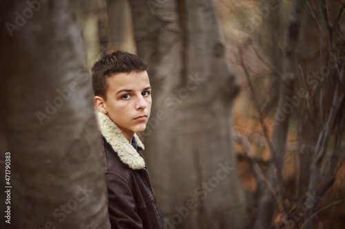 young teenager stands in the woods in late November