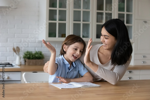 Fotografija Little cute boy finish schoolwork giving high five to Asian tutor