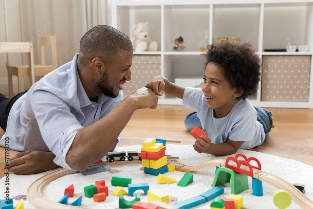 © fizkes - Proud dad and happy little son bumping fists over toy blocks and railway model on heating floor. Father giving praise to kid, expressing approval, enjoying friendship, fatherhood, playtime © fizkes - Proud dad and happy little son bumping fists over toy blocks and railway model on heating floor. Father giving praise to kid, expressing approval, enjoying friendship, fatherhood, playtime