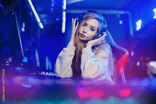 Professional cyber video gamer woman in studio room with personal computer armchair, neon color blur background