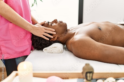 Young african american man having face massage at beauty center