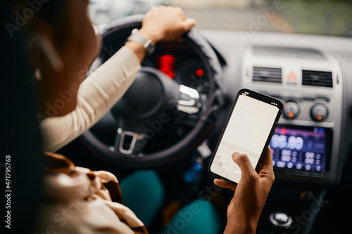 Close-up of woman text messaging on mobile phone while driving car.