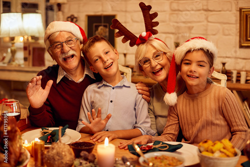 Joyful grandparents and grandkids have fun on Christmas and wave to camera. photo