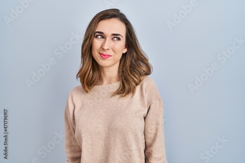 Young woman standing over isolated background smiling looking to the side and staring away thinking.