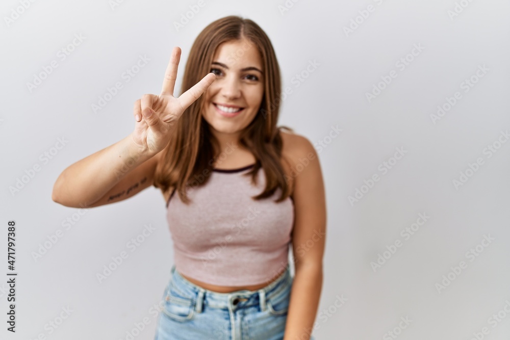 Young brunette woman standing over isolated background showing and pointing up with fingers number two while smiling confident and happy. Young brunette woman standing over isolated background showing and pointing up with fingers number two while smiling confident and happy.