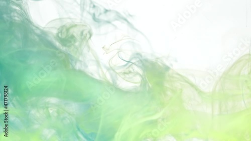 Mix of green and yellow color paints swirls in transparent water as decorative abstract background slow motion extreme close view