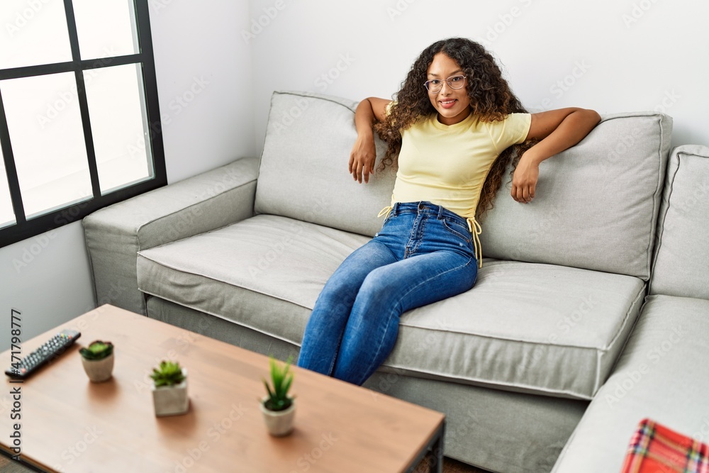 Young latin woman smiling confident sitting on the sofa at home