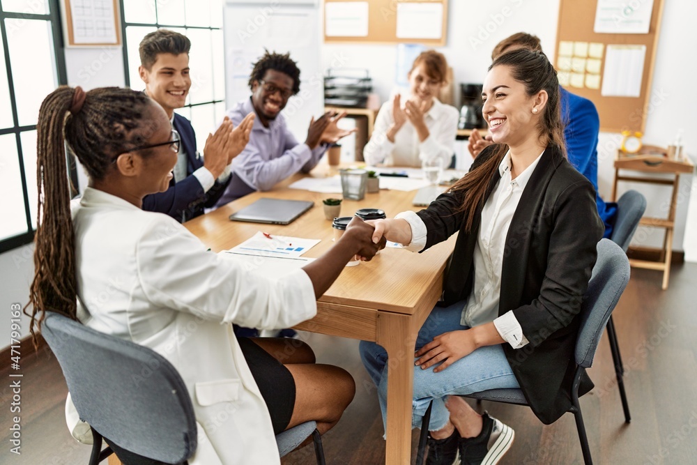 Group of business workers smiling and clapping to partners handshake at the office.